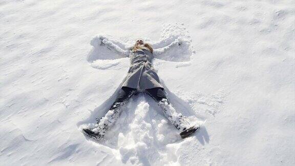 慢镜头:快乐的女人在新雪中做天使