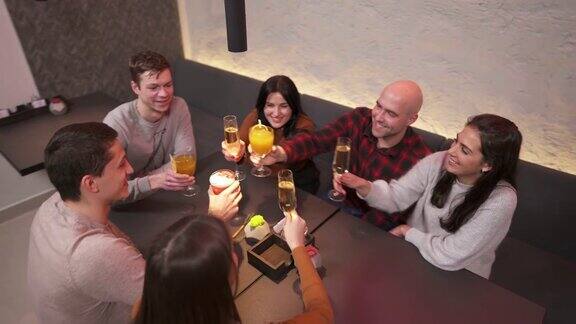 顶视图的年轻公司有乐趣在酒吧他们坐在桌旁碰杯庆祝朋友是快乐的;他们在一个好地方喝酒享受夜晚