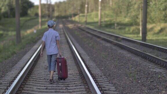 有趣的男孩带着旅行袋坐火车在户外