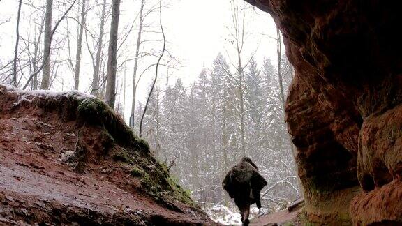史前穴居人走出洞穴背景是冬天的森林