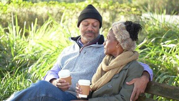 非裔美国夫妇在公园长椅上休息喝咖啡
