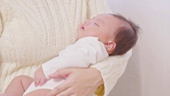 可爱的睡着的新生儿放松在妈妈的手臂安全舒适微笑亚洲新生儿宝宝休息睡觉香甜的梦母亲抱着婴儿新生儿