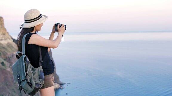 迷人的年轻女摄影师戴着帽子用专业相机拍照或录像