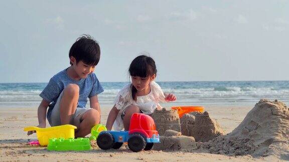 男孩和女孩在海滩上玩沙盒快乐的一家人在海滩上享受暑假节日假期iStock
