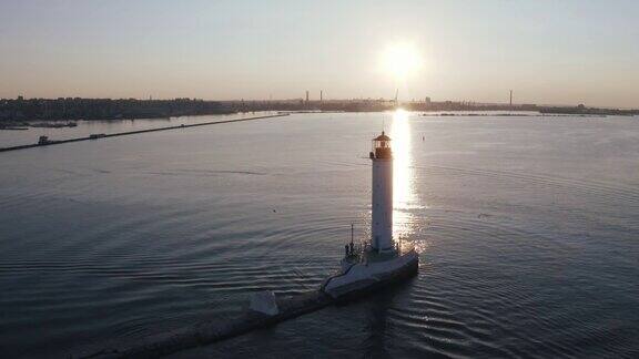 航拍海港附近的白色灯塔在日落时的剪影