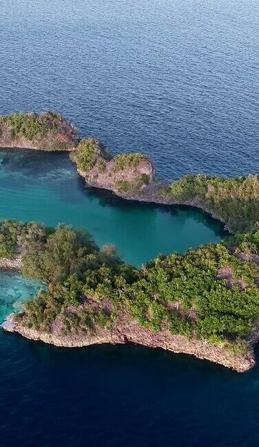 垂直视频的空中拍摄的热带岩石岛与蓝绿色的水和浅礁