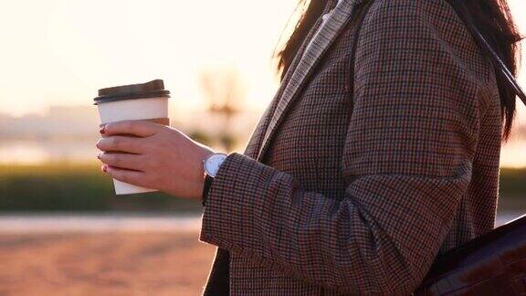 早上拿着纸制咖啡杯散步的女人