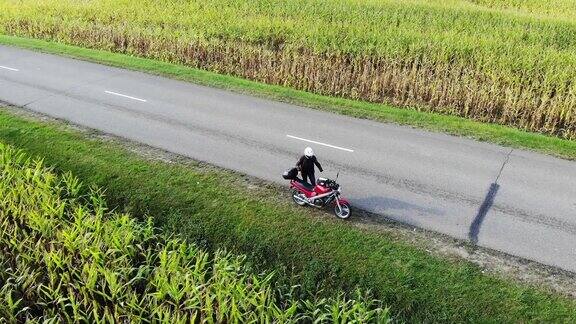 日落时分骑摩托车在乡村公路上行驶无人机拍摄的美丽冒险旅行镜头高空拍摄