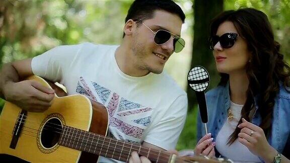 一个男人在野餐时给他的女朋友弹吉他特写