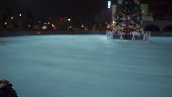 在隔离、冠状病毒和covid-19大流行期间一名蒙面男子站在溜冰场附近装饰好的圣诞树空无一人晚上去溜冰场溜冰一个空的公共溜冰区