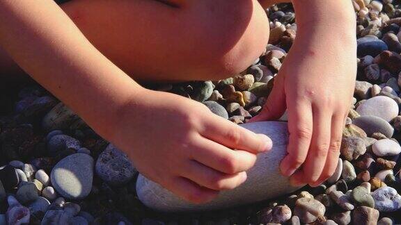 一个孩子在沙滩上玩石头特写
