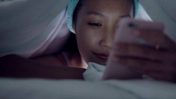 年轻女人晚上在床上玩手机