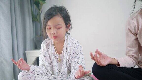 快乐的亚洲女孩做冥想与她的妹妹一起在家里生活理念
