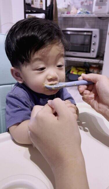 快乐的亚洲小男孩在家里吃着妈妈喂的软软的食物