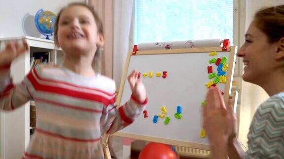 年轻的母亲在家给可爱的小女儿讲解算术