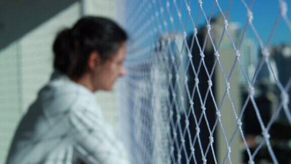 女人站在阳台上看城市风景公寓围栏网防安全