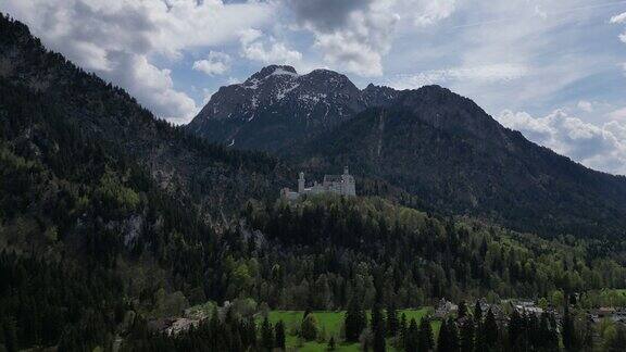 多云的天空中德国阿尔卑斯山绿色山丘上的新天鹅堡风景