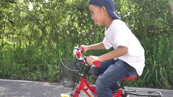 亚洲小男孩在花园里学骑和摔倒自行车学骑自行车