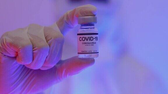 亚洲医生手持并展示Covid-19疫苗瓶