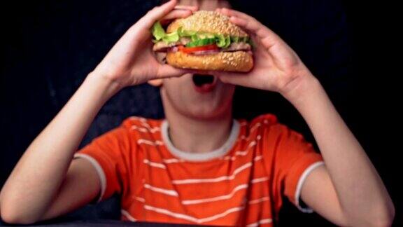 年轻快乐的少年吃着美味的汉堡