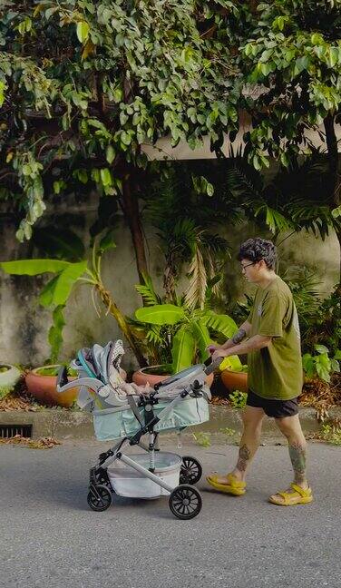 快乐的亚洲父亲和坐在婴儿车上的小男孩散步