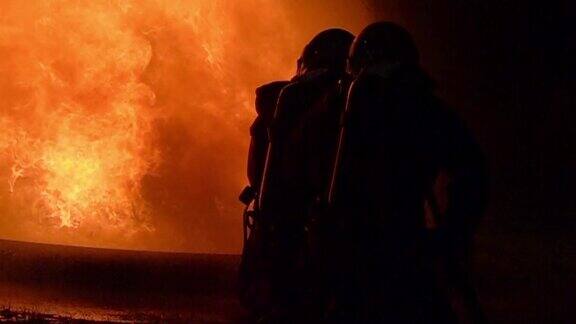 慢动作消防队员使用旋转水雾式灭火器与油中的火焰进行搏斗以控制火势不扩散消防员与工业安全理念