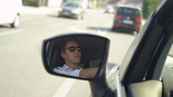 近距离观察:汽车侧镜中快乐男子驾车穿过城镇的画面