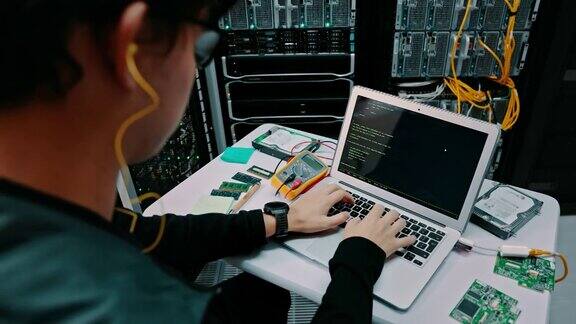 一名男性开发人员在服务器室使用笔记本电脑的4k视频片段