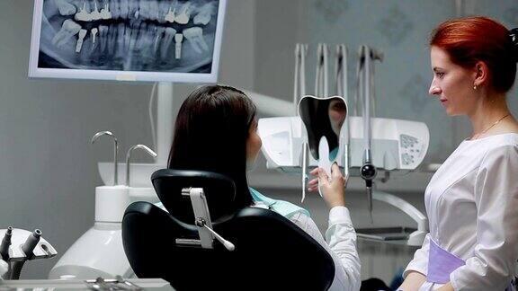 牙医和病人一起完成了他的工作移除Bor机器并给一个女孩一面镜子来评估工作女孩看着你的牙齿感谢牙医