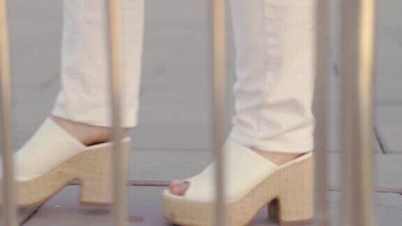 女人的脚穿着厚底鞋一个穿白裤子的女人走在铺路石上
