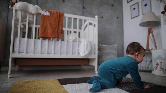 好奇的蹒跚学步的男孩在婴儿室的地毯上爬行