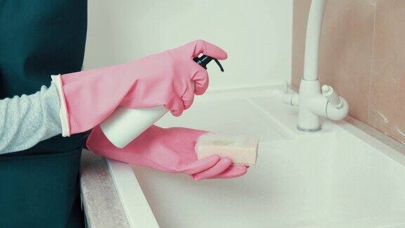 那个戴着乳胶手套的女孩的手在清洁海绵上涂了一层清洁剂