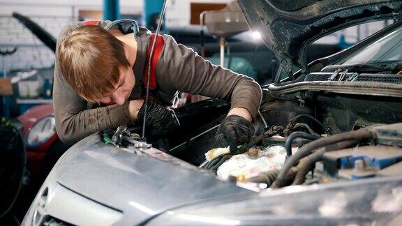 机修工检查汽车发动机修理汽车在车间工作大修引擎盖下