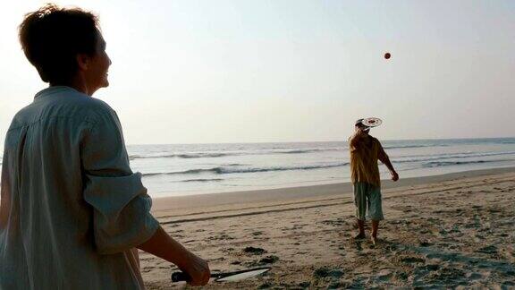 活跃的老年夫妇在沙滩上玩太极气球球