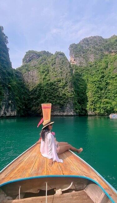 亚洲妇女在长尾船与绿色的蓝绿色泻湖在KohPhiPhi泰国
