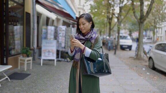 一名女子在城市人行道上查看智能手机