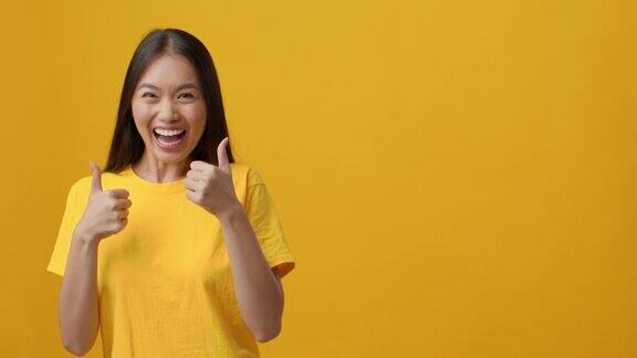 兴奋的中国女人一边手指一边竖起大拇指黄色背景