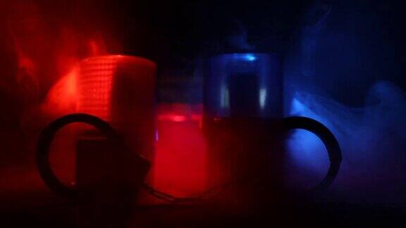 警方夜间突袭你将被逮捕手铐的轮廓和警车在后面在雾蒙蒙的背景下红色和蓝色警灯闪烁有选择性的重点