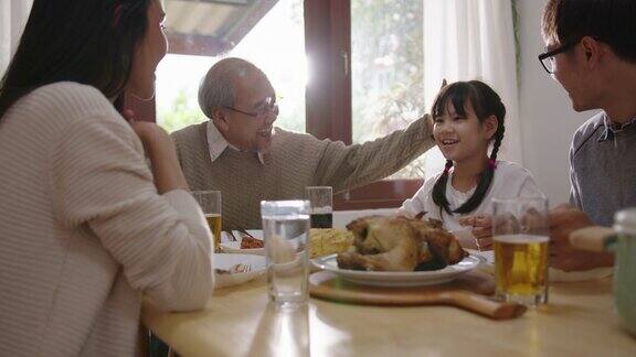 快乐的亚洲家庭共进早餐快乐的父母爷爷和可爱的女儿在家里的餐桌上一起享用早餐美妙的时刻家庭