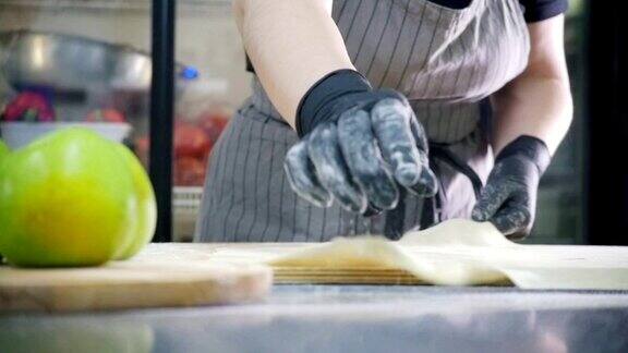 面包师在商业厨房里为苹果派准备生面团