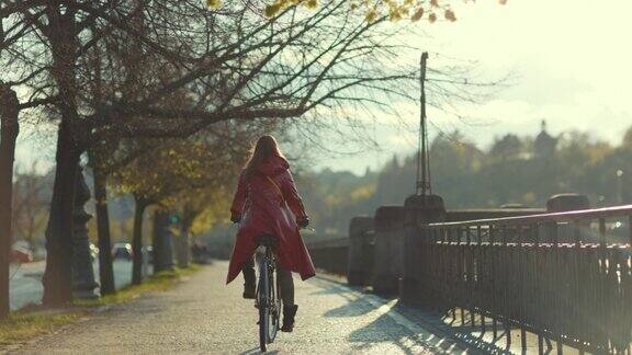 现代女性穿着红色雨衣在城市户外骑自行车