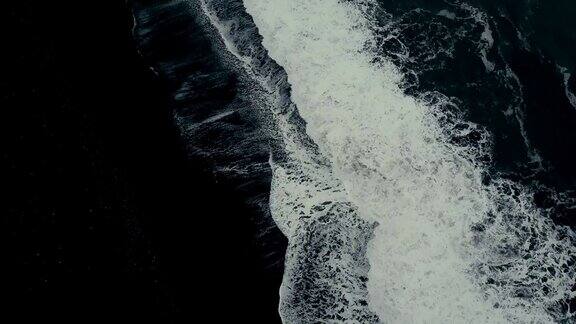 鸟瞰图的强大的波浪与泡沫来海岸上的黑色火山海滩在冰岛
