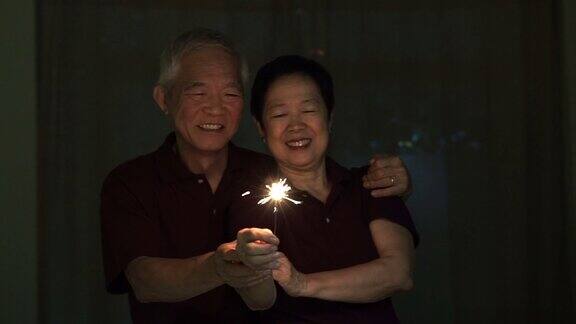 亚洲老夫妇玩烟花烟花爆竹在晚上庆祝生活