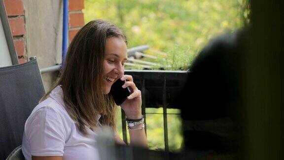 一个开朗的年轻女人在阳台上用手机聊天