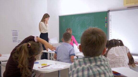 老师站在教室前面靠近黑板的地方问学生问题学生举手提问