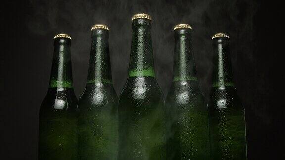 五个绿色啤酒瓶一个接一个地放在黑色的背景上
