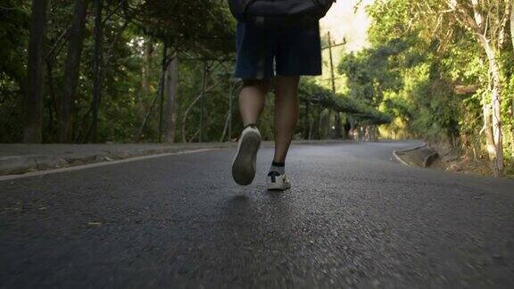 背部低角度亚洲女性徒步旅行者徒步穿越热带雨林靠近女人的腿走在小路上