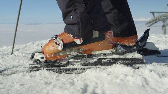 慢动作接近:滑雪者在雪道上用滑雪靴进入滑雪板绑带