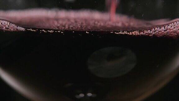 调酒师将红酒从透明的大容器中倒入玻璃杯中