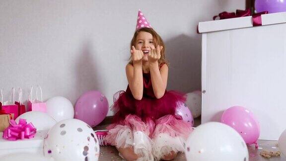 美丽的小女孩吹五彩纸屑在家里的生日派对上玩得很开心